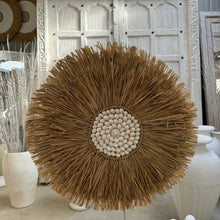 Load image into Gallery viewer, Seagrass Juju hat wall feature with a white shell centre.