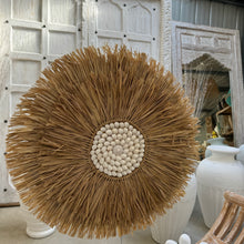 Load image into Gallery viewer, Seagrass Juju hat wall feature with a white shell centre.